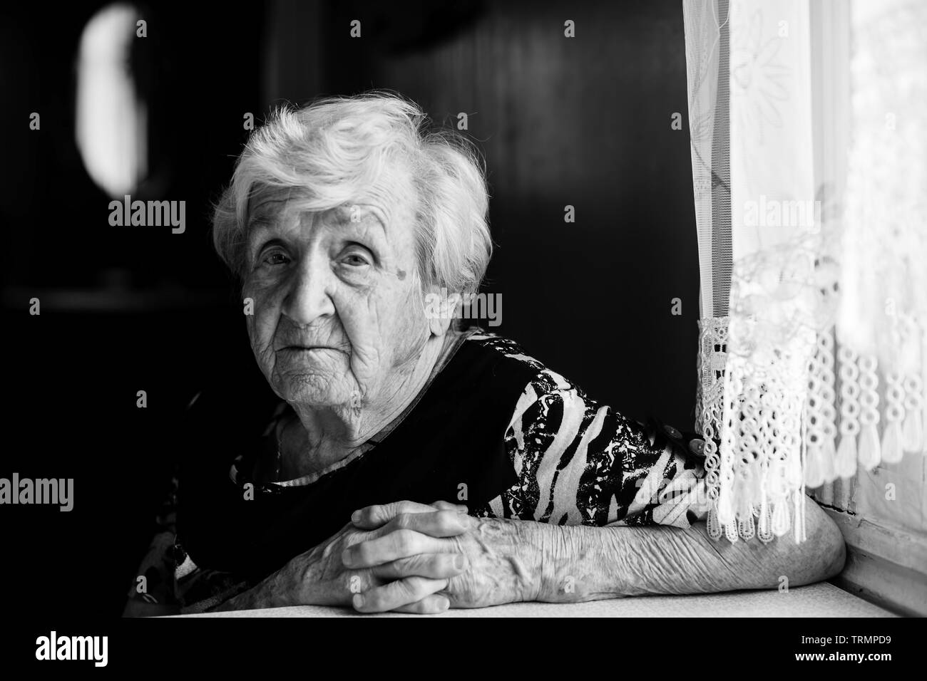 Elderly woman at his home. Black and white portrait of an old grandma. Stock Photo