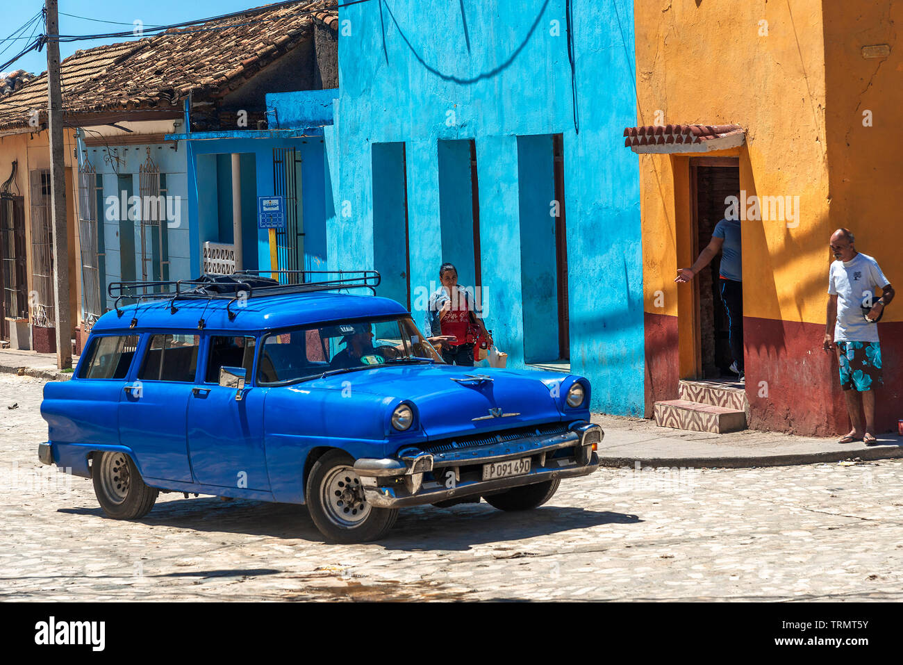 Classic American blue car driving through the picturesque  cobblestone streets of the colonial town of Trinidad, Sancti Spiritus, Cuba, Caribbean Stock Photo