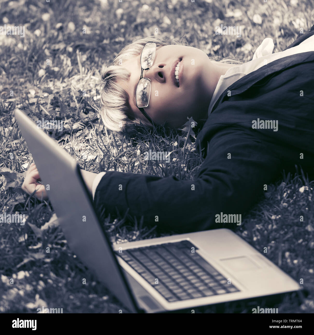 Happy business woman with laptop lying on the grass Stock Photo - Alamy