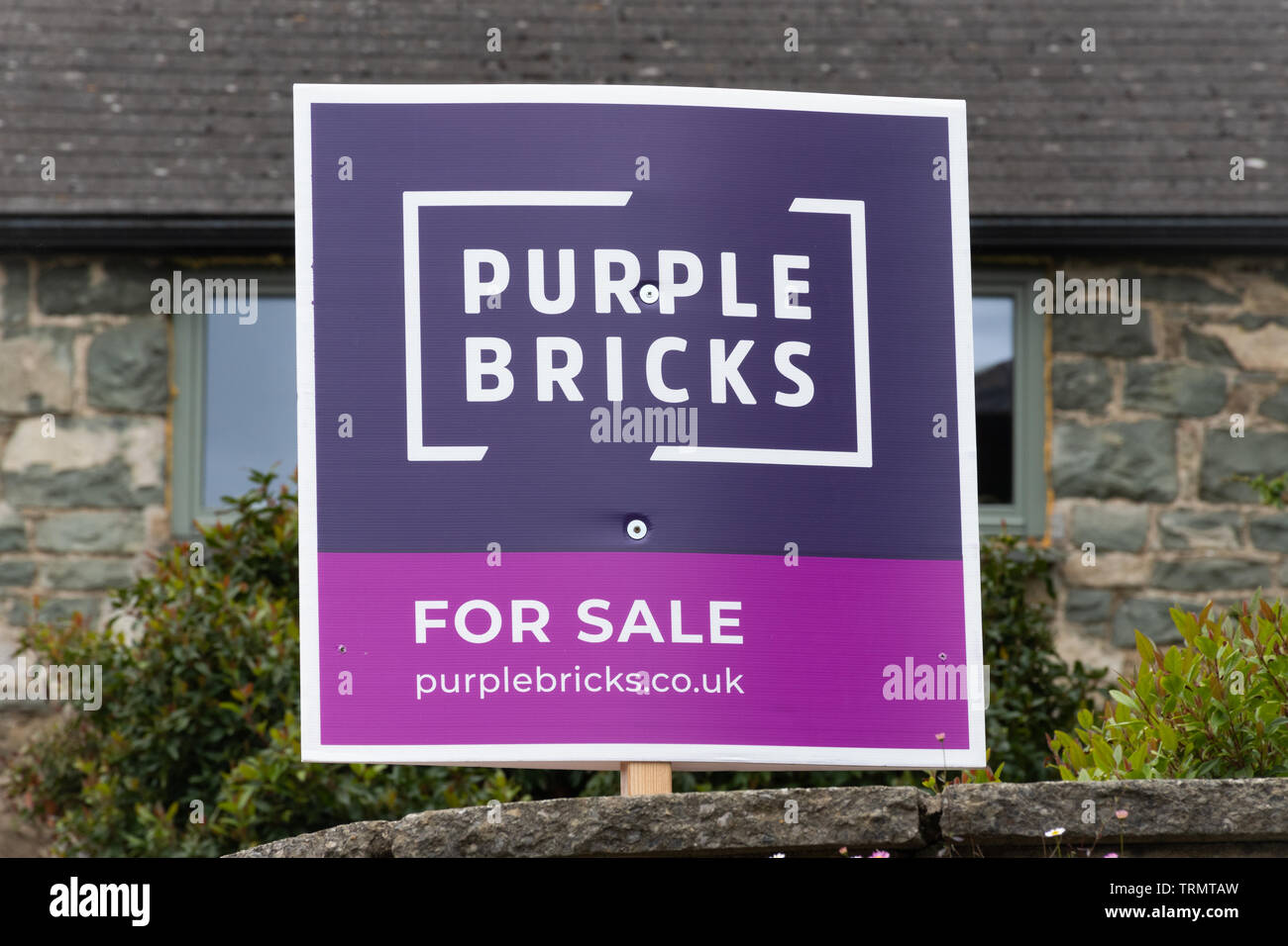 Purple bricks estate agents for sale sign outside a house, UK Stock Photo