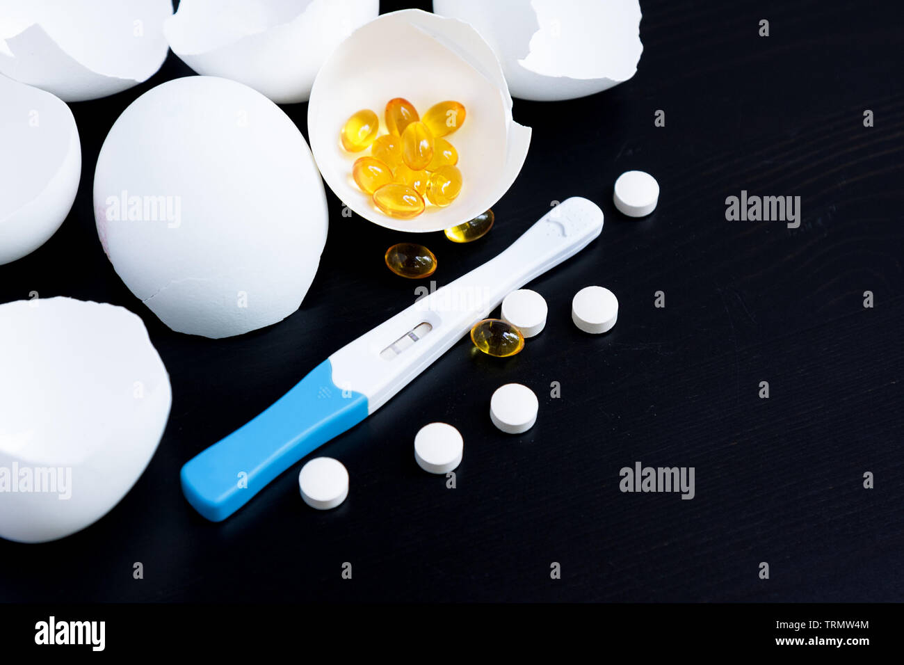Infertility. Negative pregnancy test and eggshell on black background