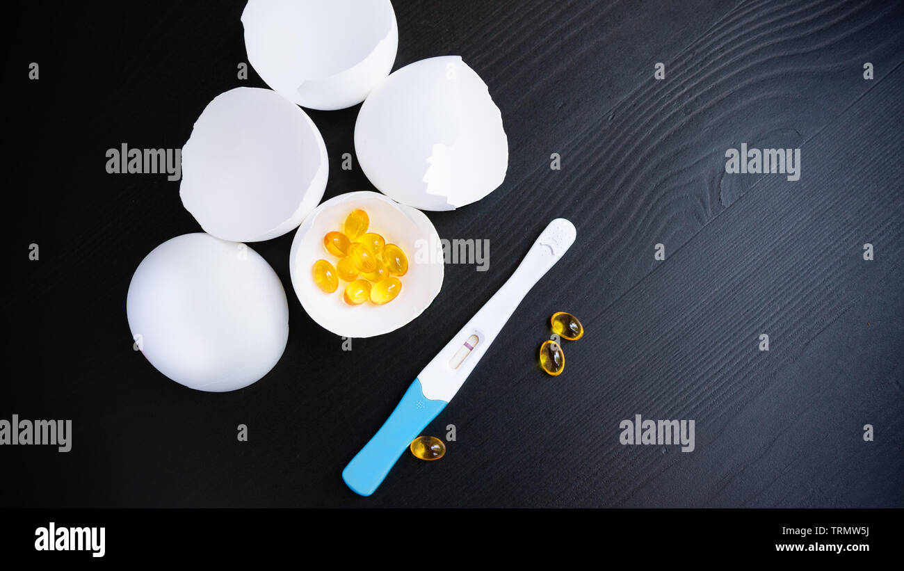 Infertility. Negative pregnancy test and eggshell on black background