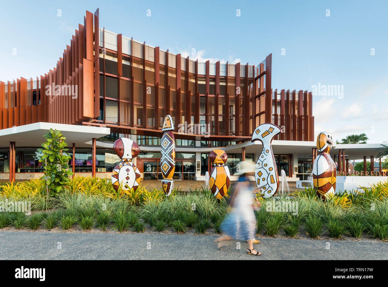Visitors walking past the 'Bagu' indigenous sculptures in front of the Cairns Performing Arts Centre, Cairns, Queensland, Australia Stock Photo
