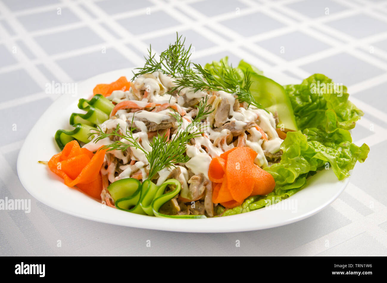 salad of boiled beef, champignons, carrots, pickled cucumbers, onions and lettuce seasoned with mayonnaise. Stock Photo