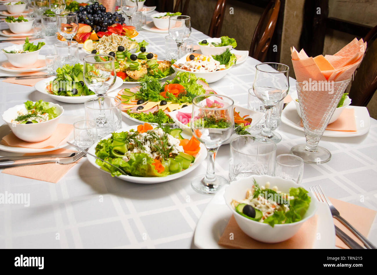 table lined with variety of dishes from which the centerpiece is dish with banquet cutting with ham and dish with several tartlets with chicken and ha Stock Photo