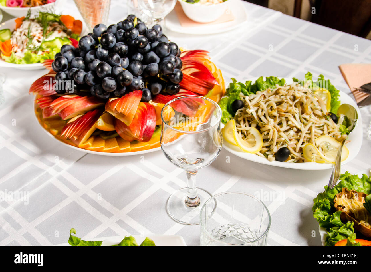 table lined with variety of dishes from which the centerpiece is dish with sliced fruit. Stock Photo
