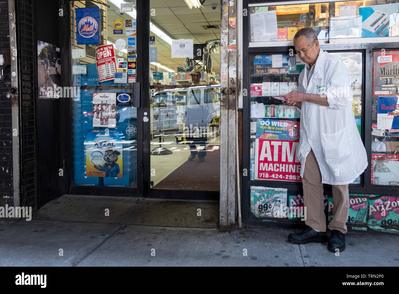An older man checking his scratch off lottery ticket outside a small grocery store on Roosevelt Ave. under the el in Jackson heights, Queens, New York. Stock Photo