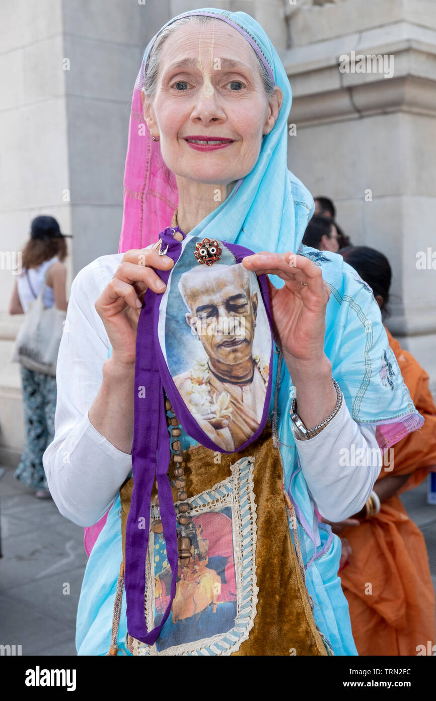 A middle aged Hindu devotee poses for a picture with a pocketbook that has a photo of Srila Prabhupada, the founder of the Hare Krishna movement. Stock Photo