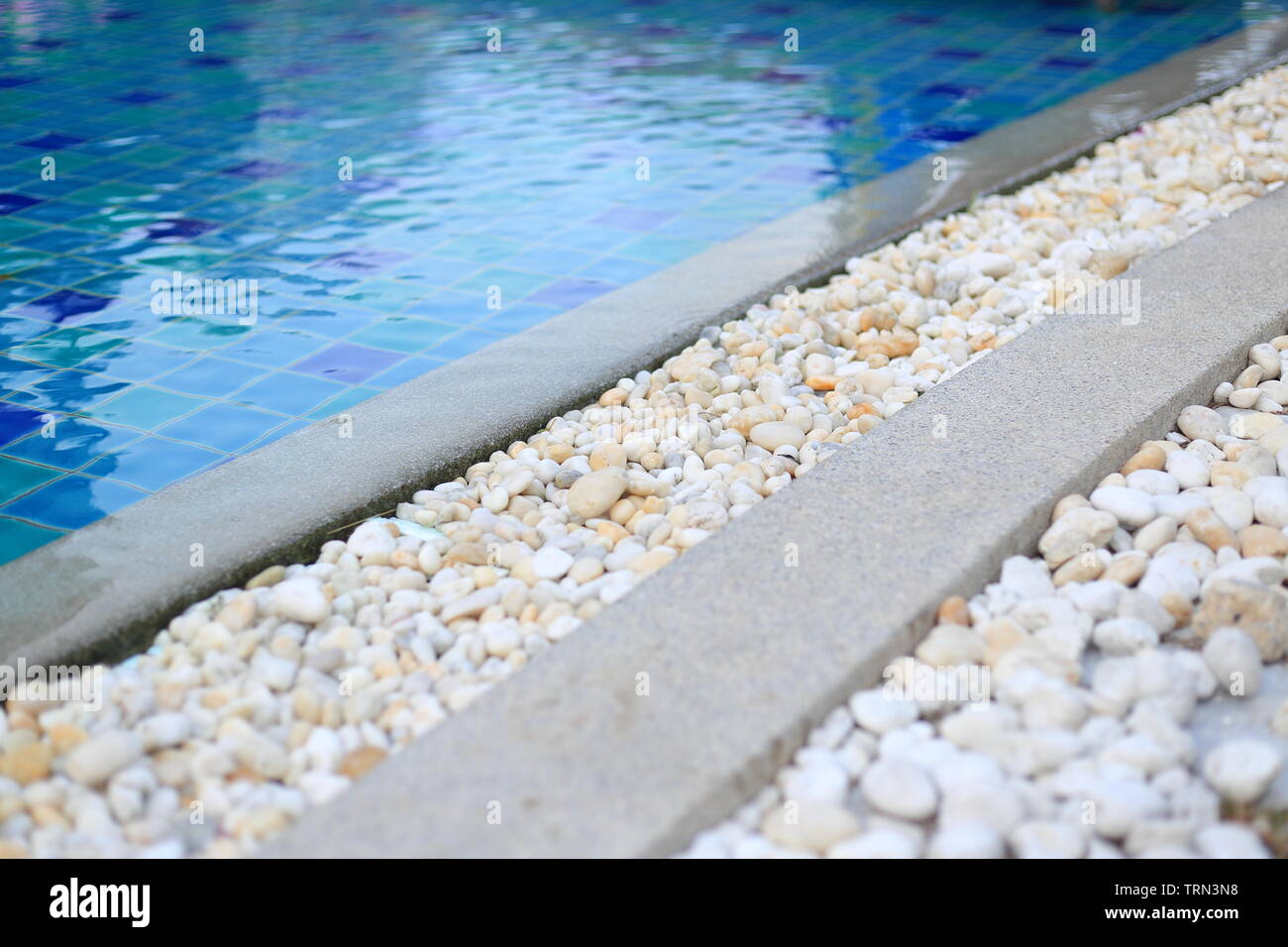 swimming pool grating covered with round white river pebble. drainage system separate lawn and pool covered with white stone. swimming pool drainage Stock Photo