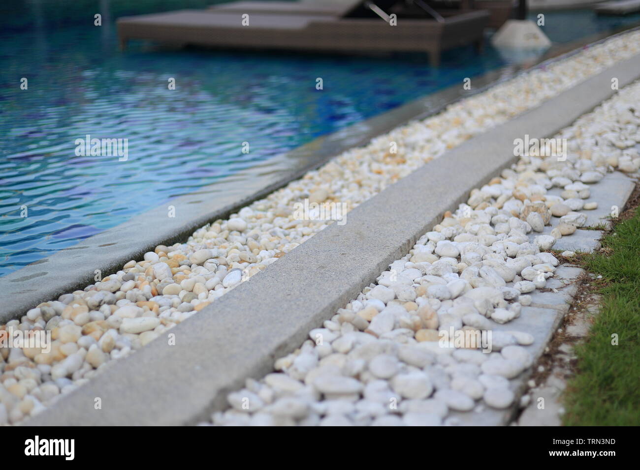 swimming pool drainage system grating covered with round white river stone pebble. swimming pool architectural detail design. White pebble contrasting Stock Photo