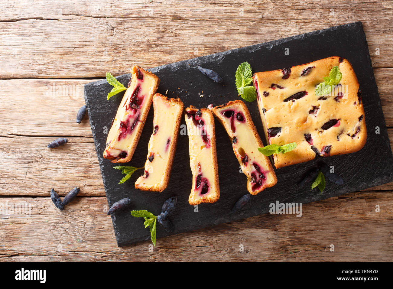 Berry cake with honeysuckle and mint on the board closeup on a wooden table. Horizontal top view from above Stock Photo