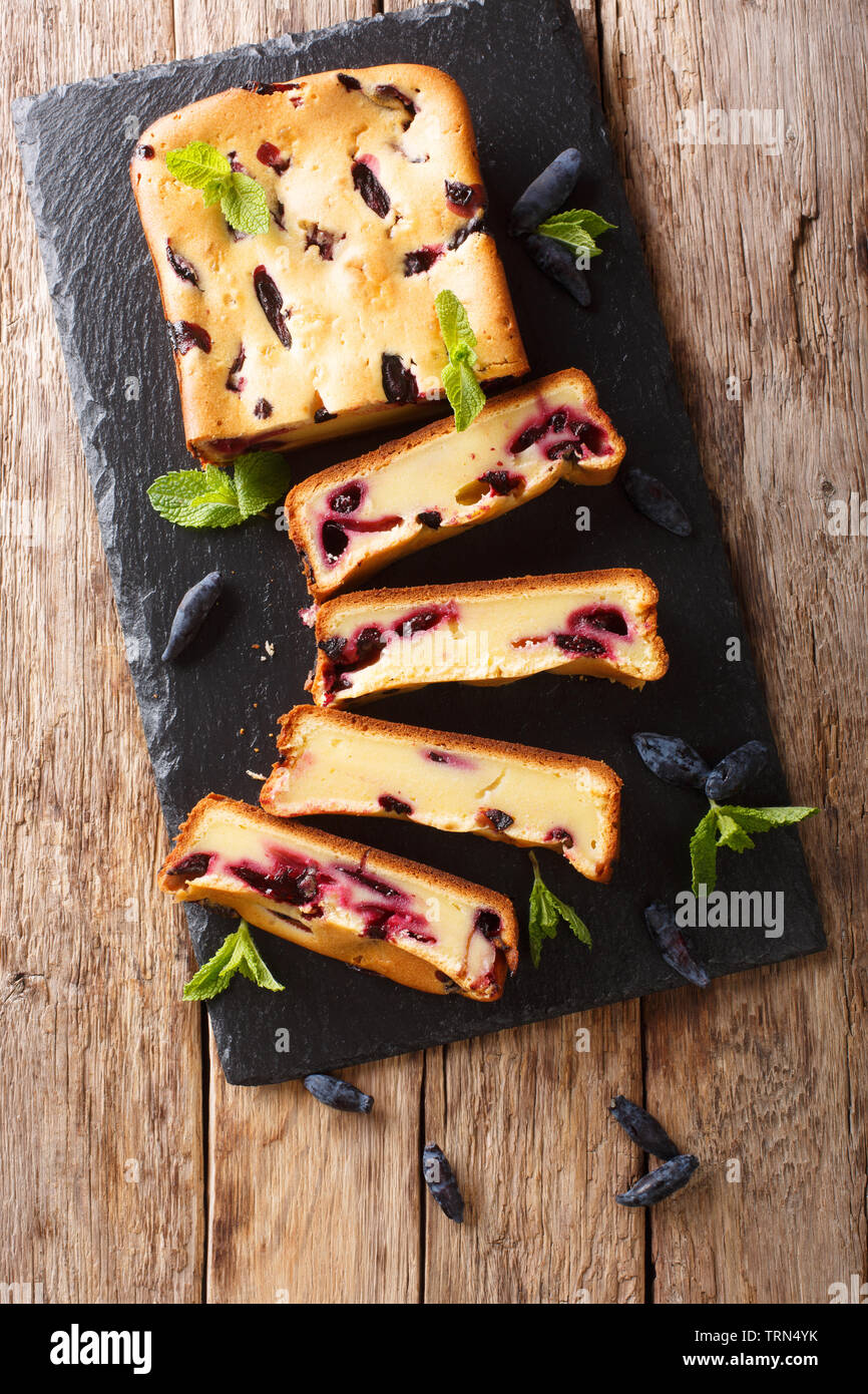 Berry cake with honeysuckle and mint on the board closeup on a wooden table. Vertical top view from above Stock Photo