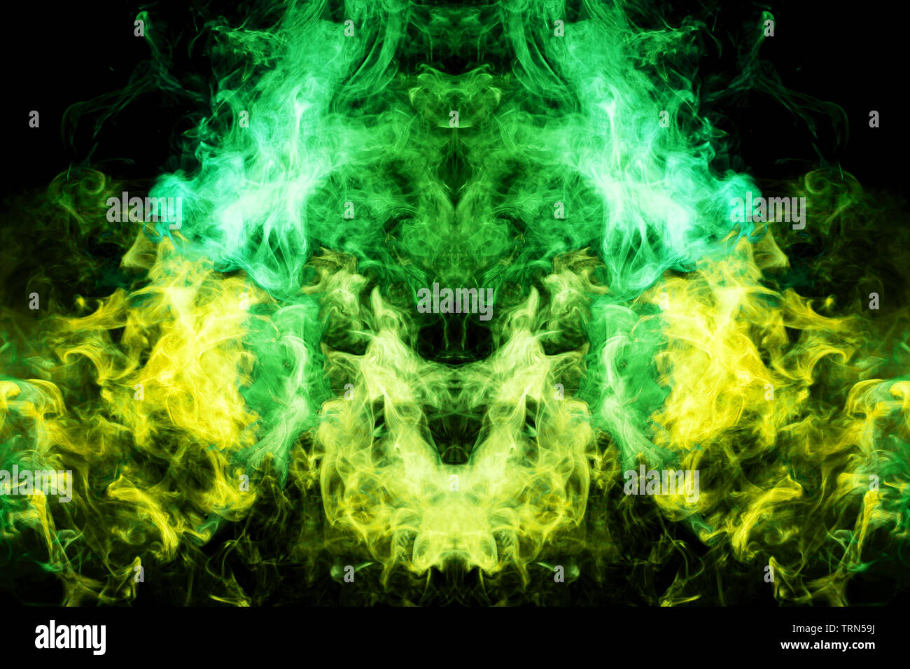 Thick colorful smoke of green and yellow in the form of a skull, monster,  dragon on a black isolated background. Background from the smoke of vape. M  Stock Photo