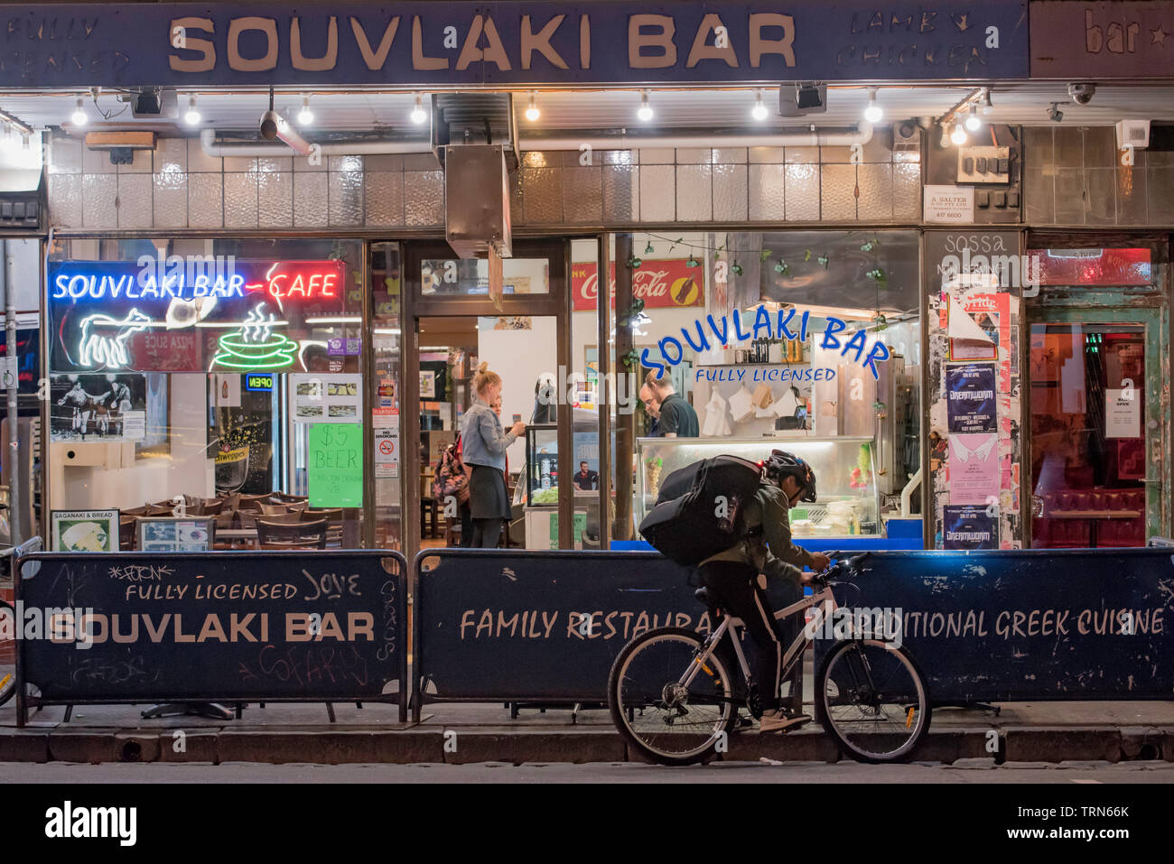 A food delivery cyclist at night outside a Greek souvlaki bar on Brunswick Street, Fitzroy