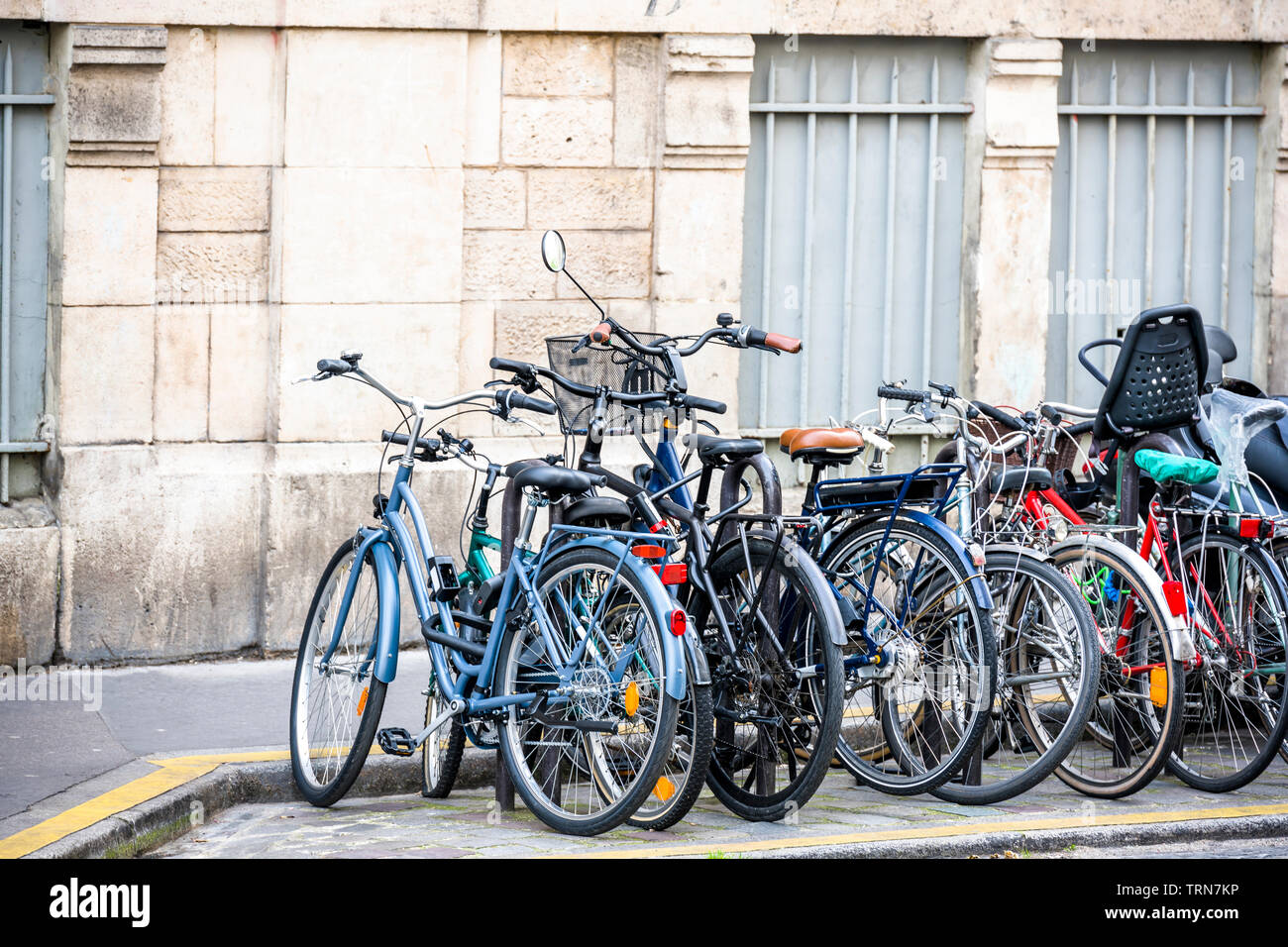 Bunch of different bicycles of local Parisians stand along the old building on the street ready to take cyclists for bike trip to any point of old his Stock Photo