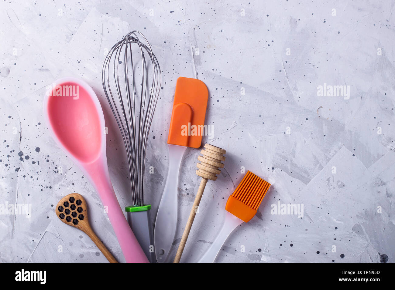 Tools for making desserts - spoon, whisk, spatula for dough, honey, creams on a gray table Stock Photo