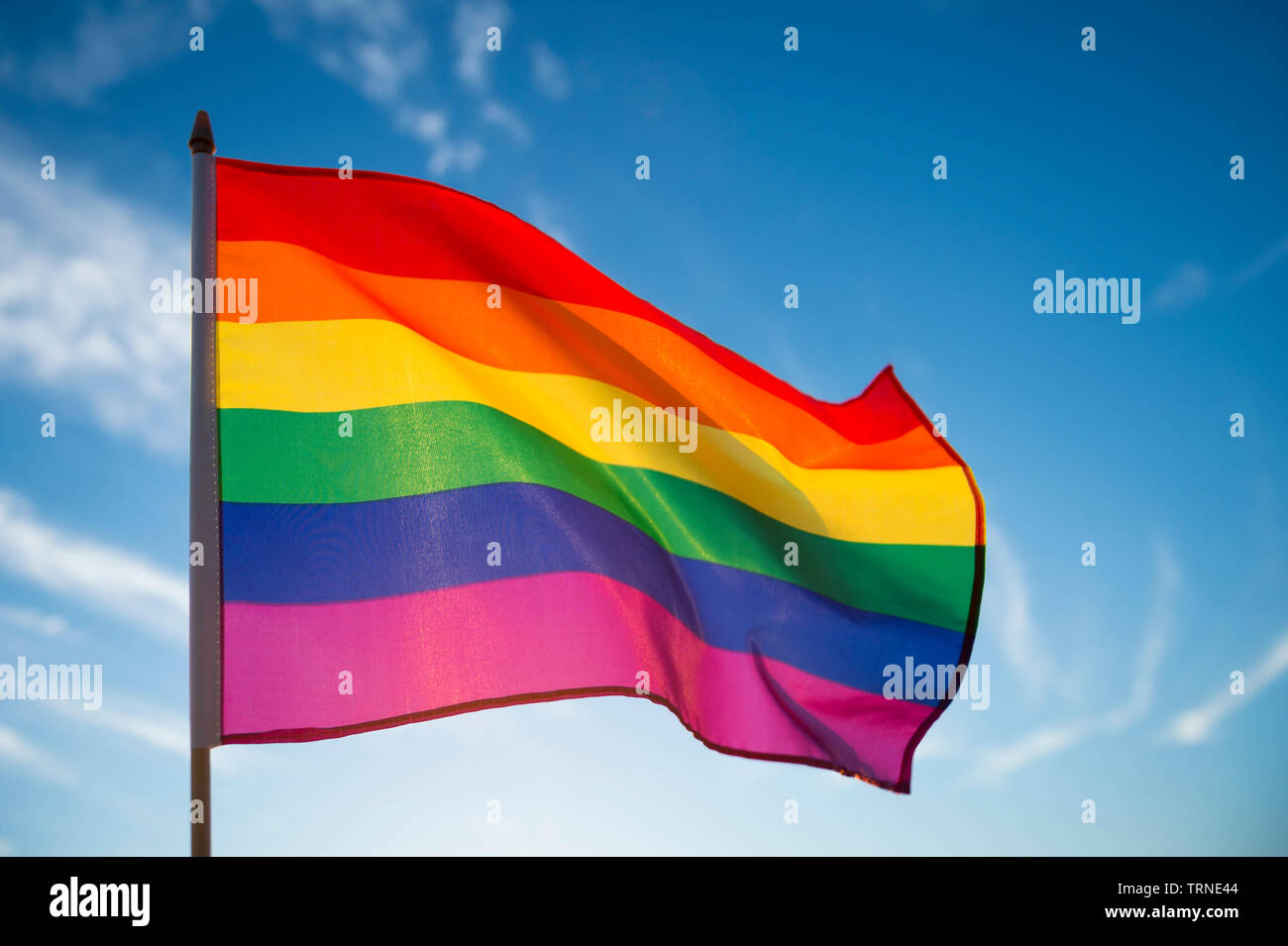 Gay Pride Rainbow Flag Fluttering Backlit In The Sun Against Soft Blue Sky Copy Space Stock Photo Alamy