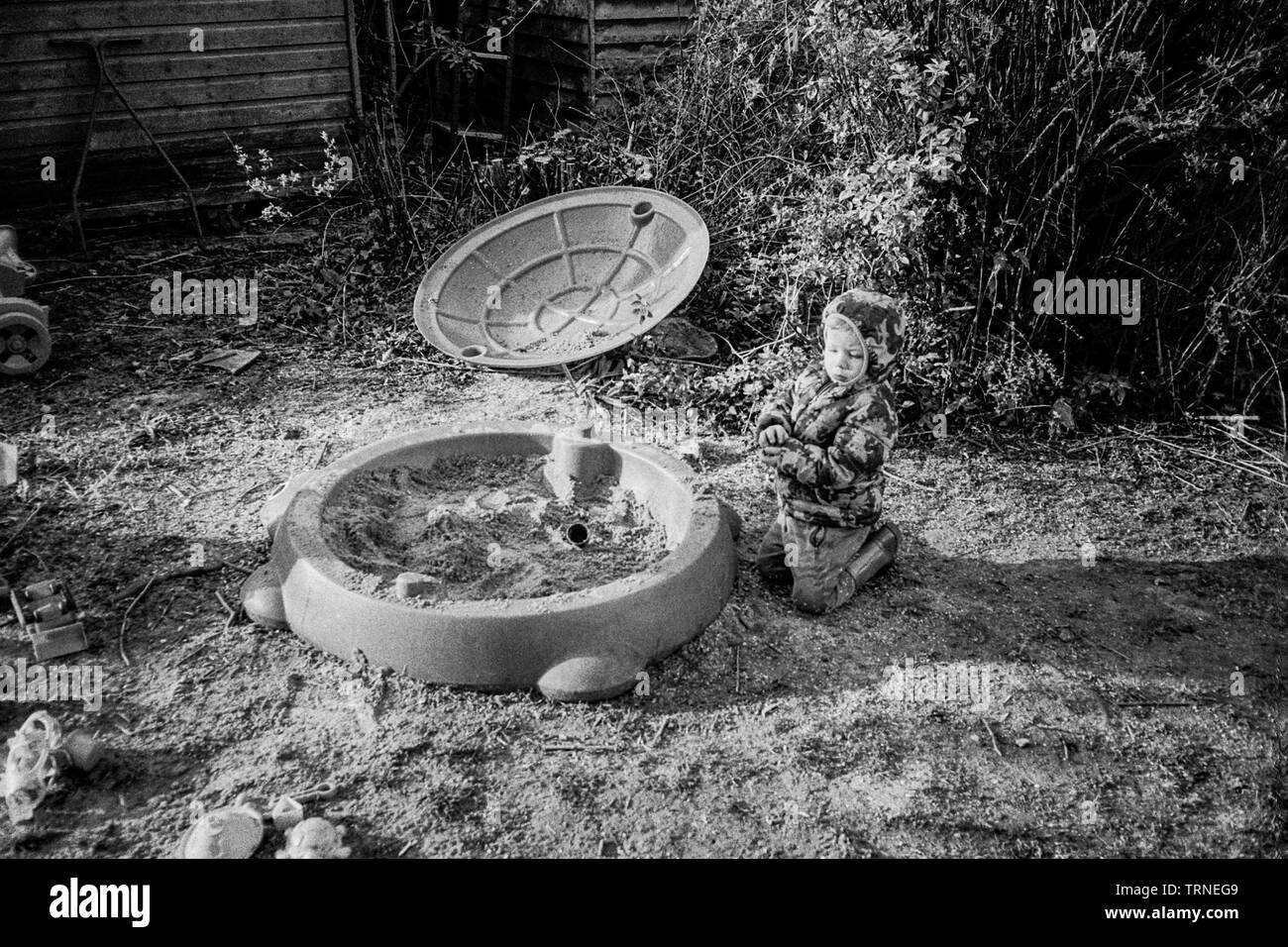 Two year old boy playing in a sand pit, Medstead, Alton, Hampshire, England, United Kingdom. Stock Photo