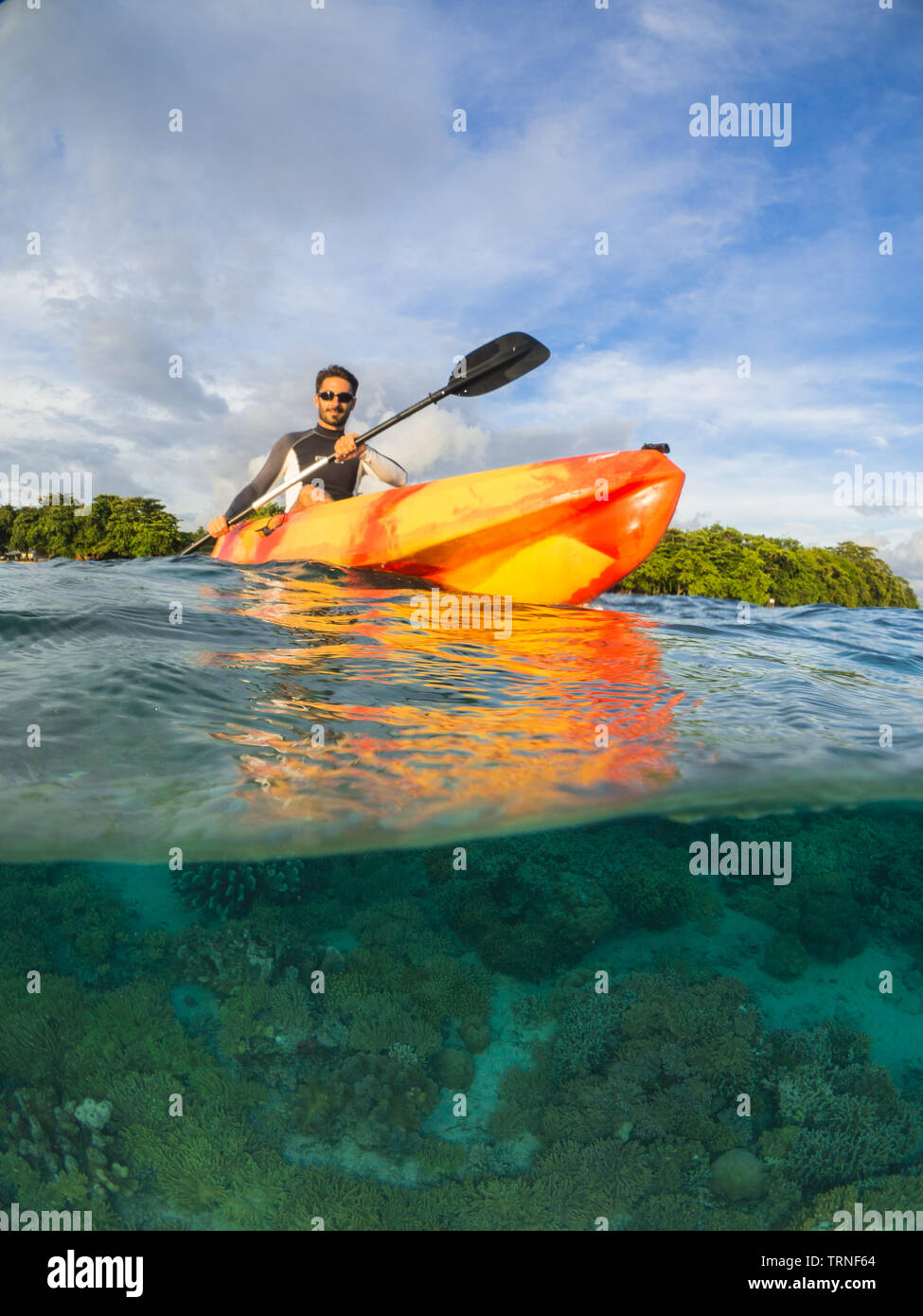 Man kayaking from an island above a colorful coral reef underwater in Bunaken Marine Park, North Sulawesi, Indonesia Stock Photo