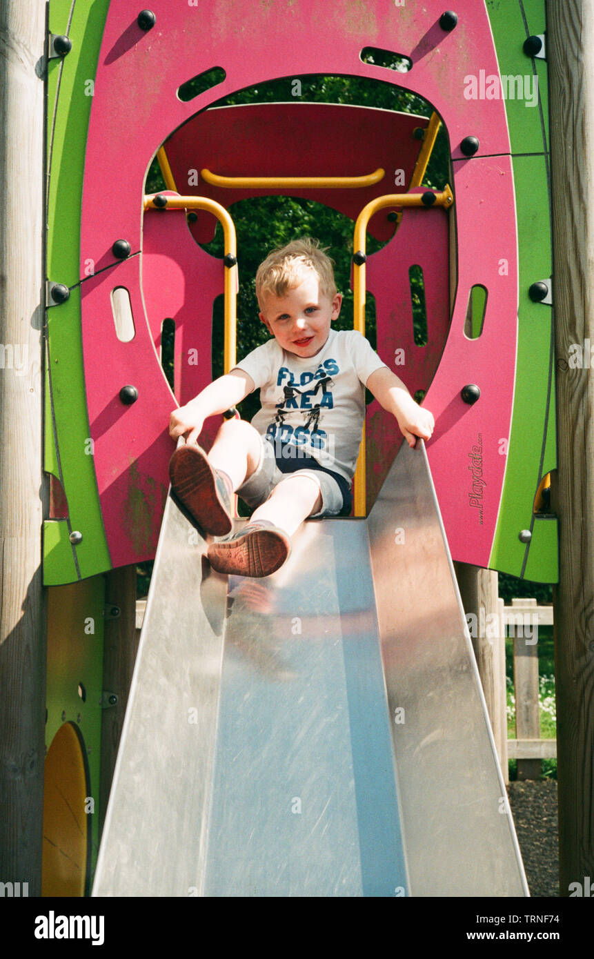 Two year old boy on a playground slide, Medstead, Alton, Hampshire, England, United Kingdom