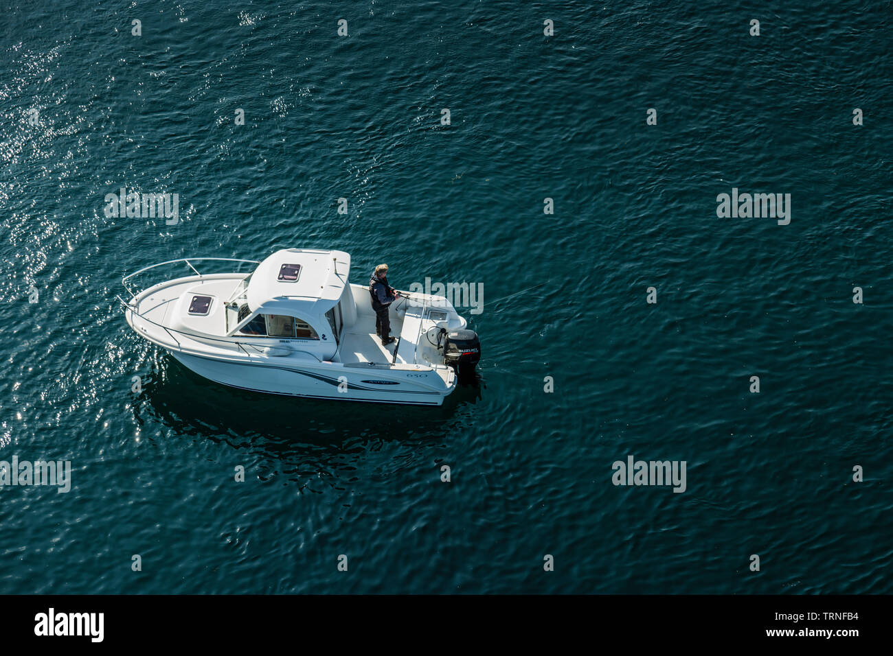 A man fishing from a boat in mid channel at Heroy Island, Norway, summer 2019. Stock Photo