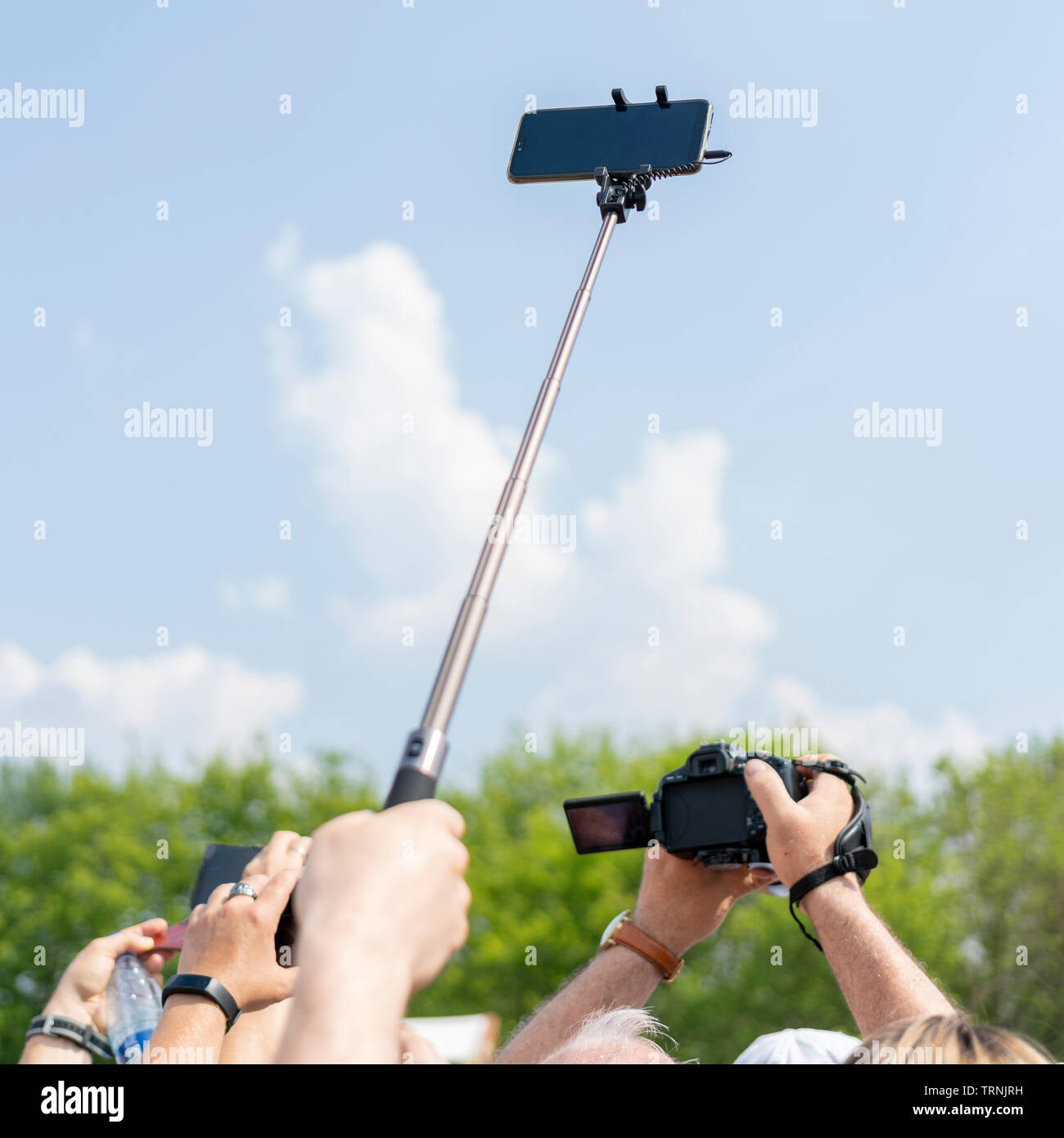Smartphone on a selfie stick in male hand against the sky Stock Photo -  Alamy