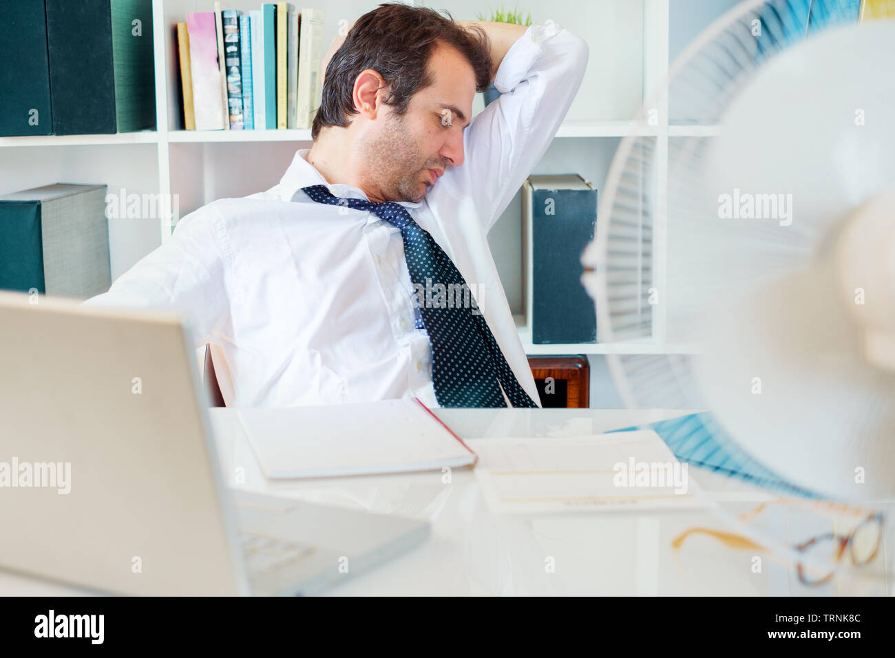 Office employee sweating and smelling and notices his sweat under armpit Stock Photo