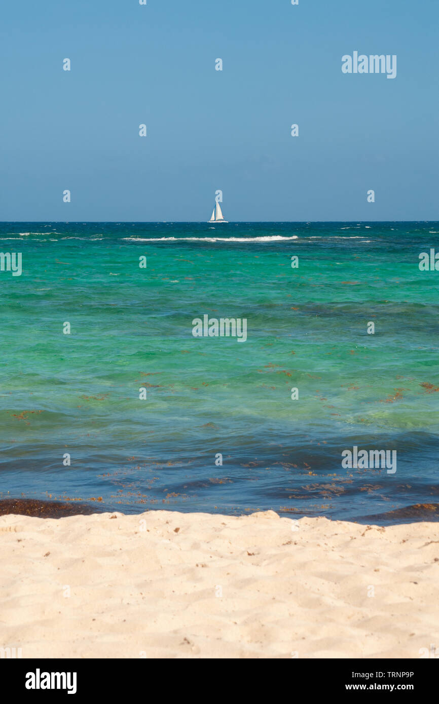 Sand and sea water, with a sailing boat in the background, taken in Tulum, in the Mexican Yucatan peninsula Stock Photo