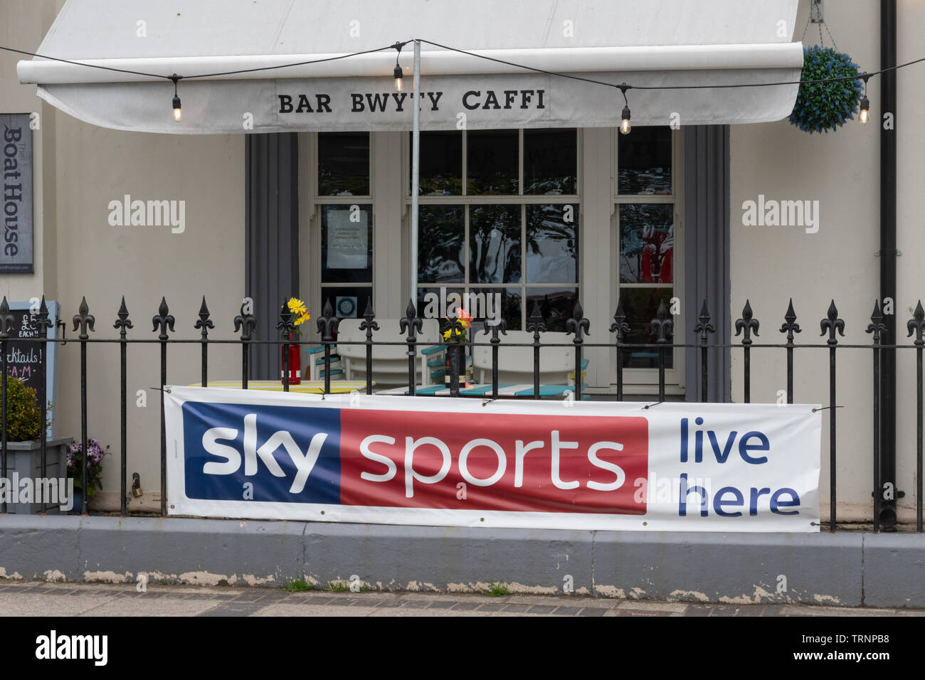 Bar (welsh language bwyty or caffi) with a Sky Sports live here advertising banner outside Stock Photo