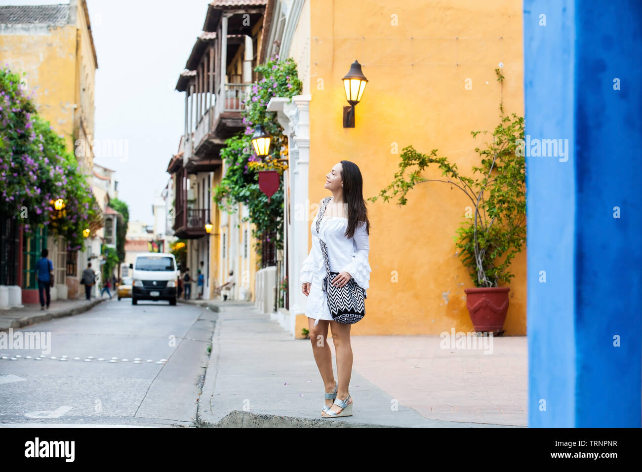 Beautiful woman on white dress walking alone at the colorful streets of the colonial walled city of Cartagena de Indias Stock Photo