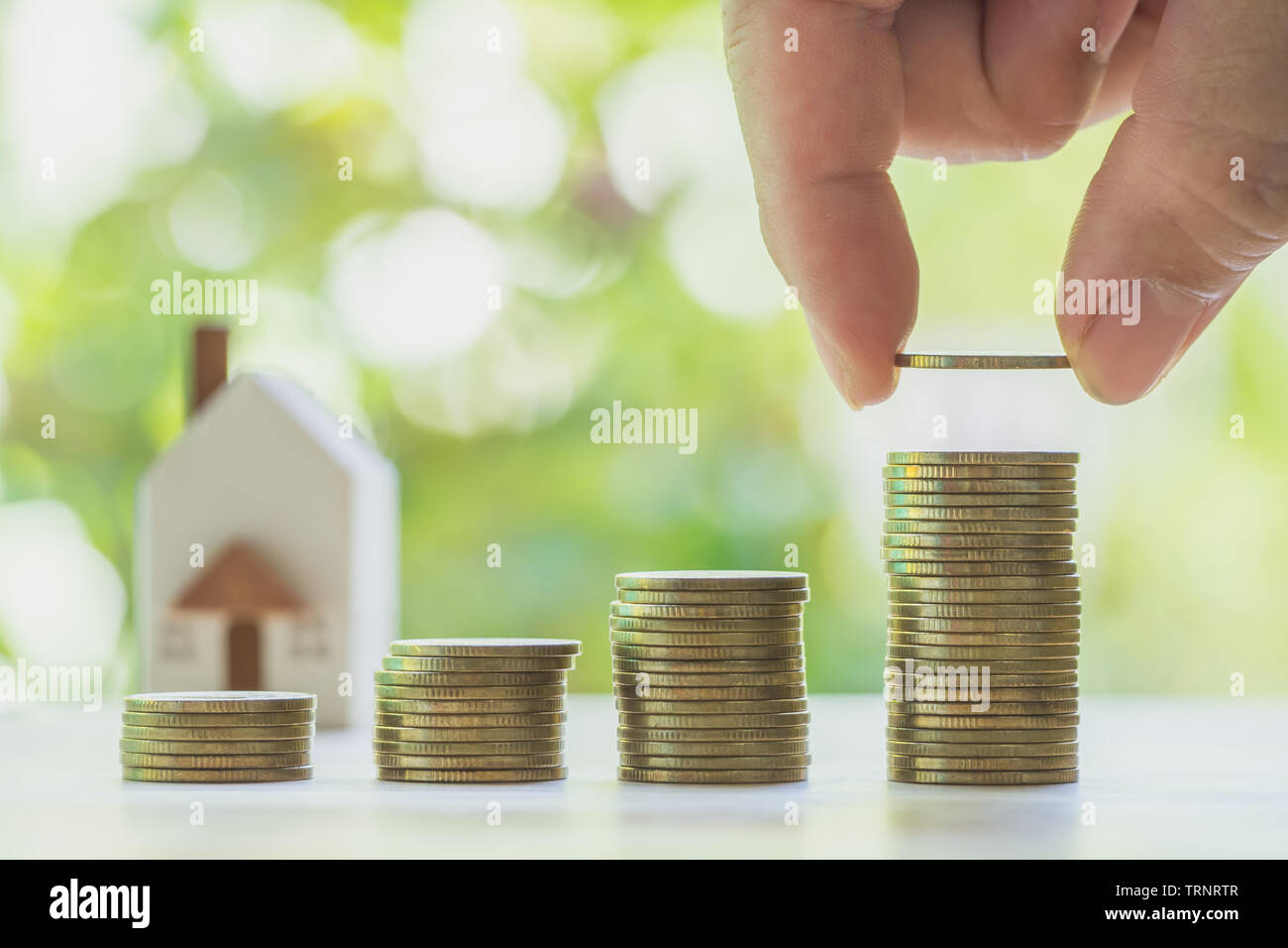 House or Home model on near of coins stack. Concept for loan, property ladder, financial, mortgage, real estate investment, taxes and bonus. Stock Photo