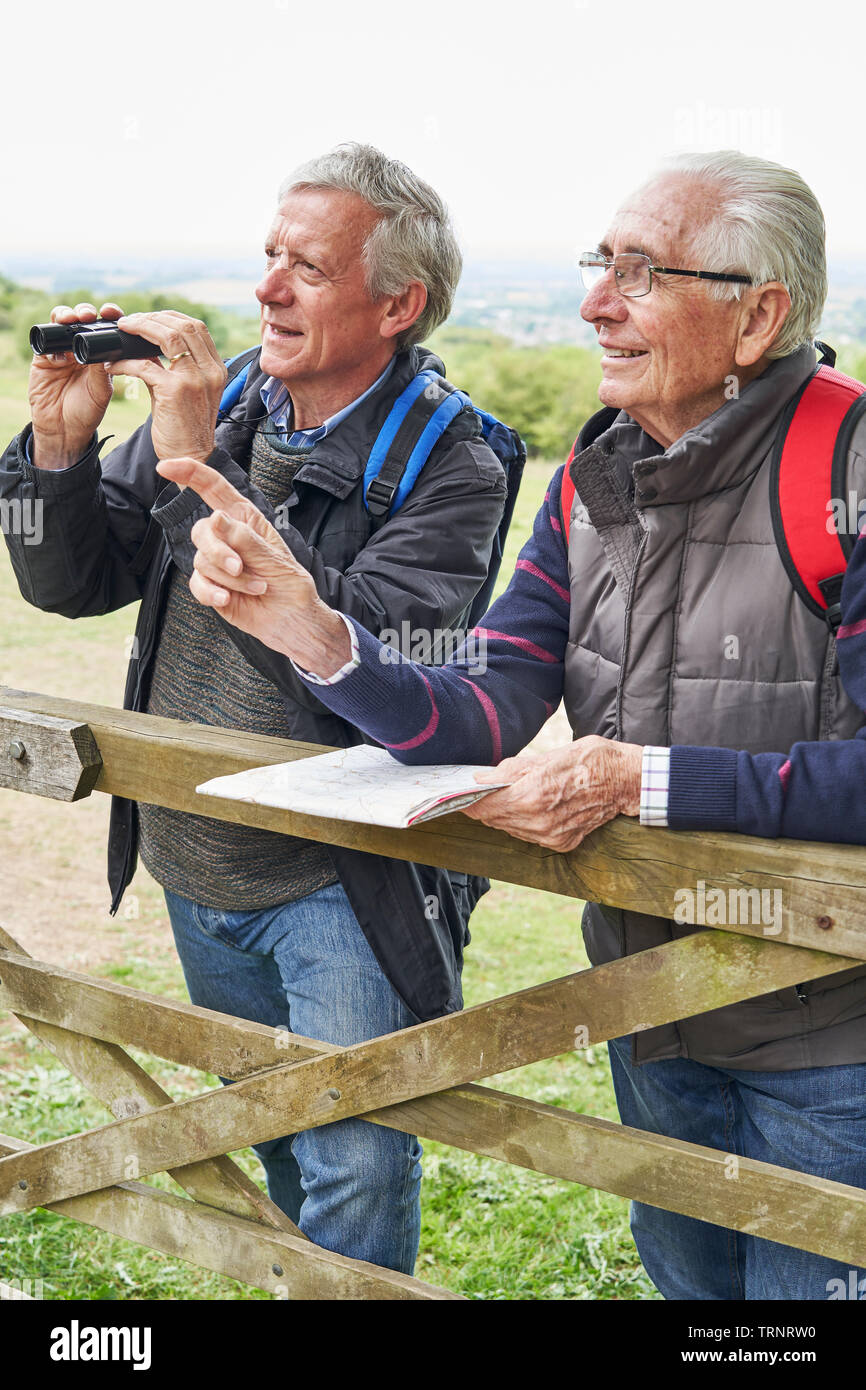 Two Retired Male Friends On Walking Holiday Looking Through Binoculars Stock Photo