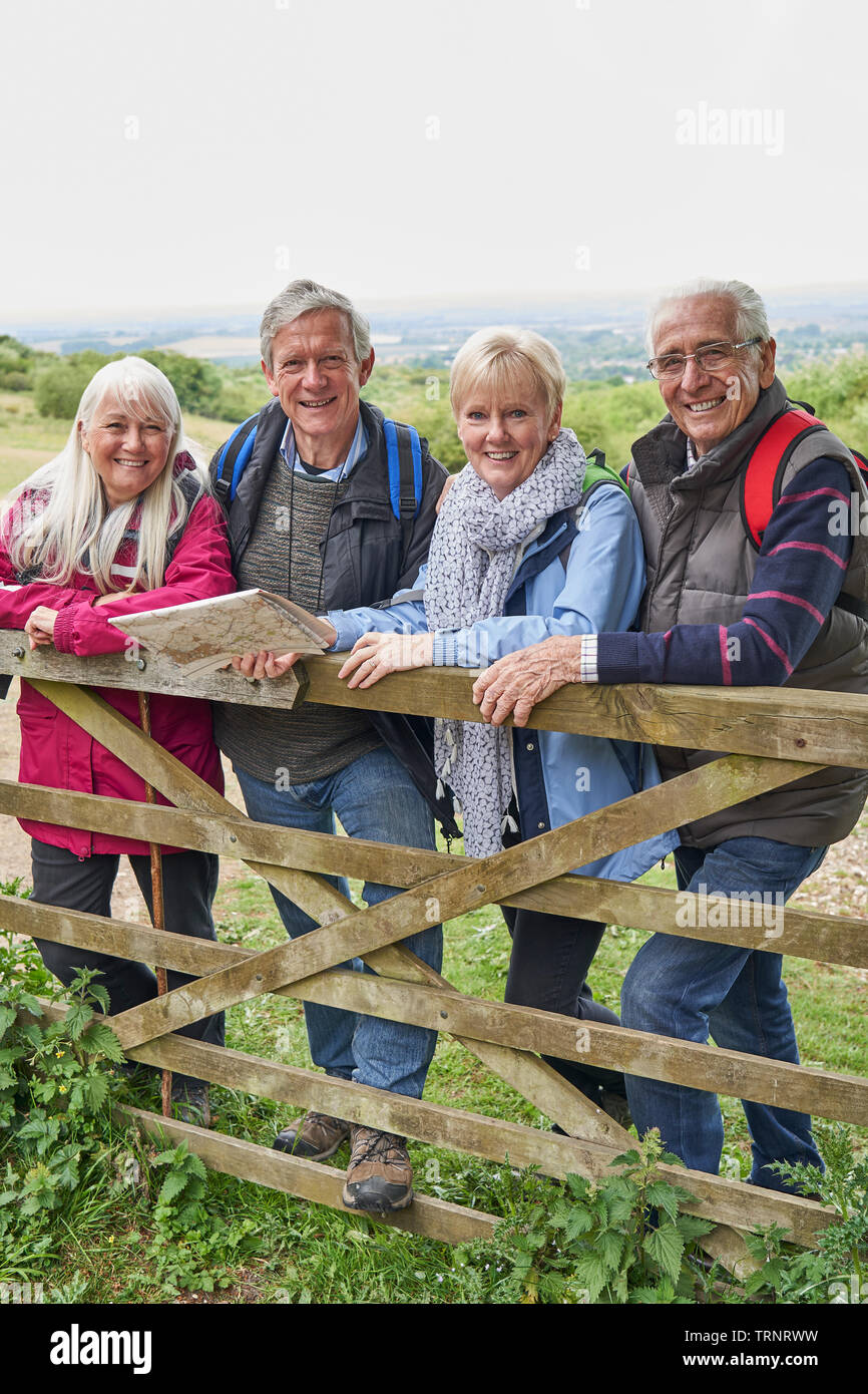 Portrait Of Group Of Senior Friends Hiking In Countryside Standing By Gate Stock Photo