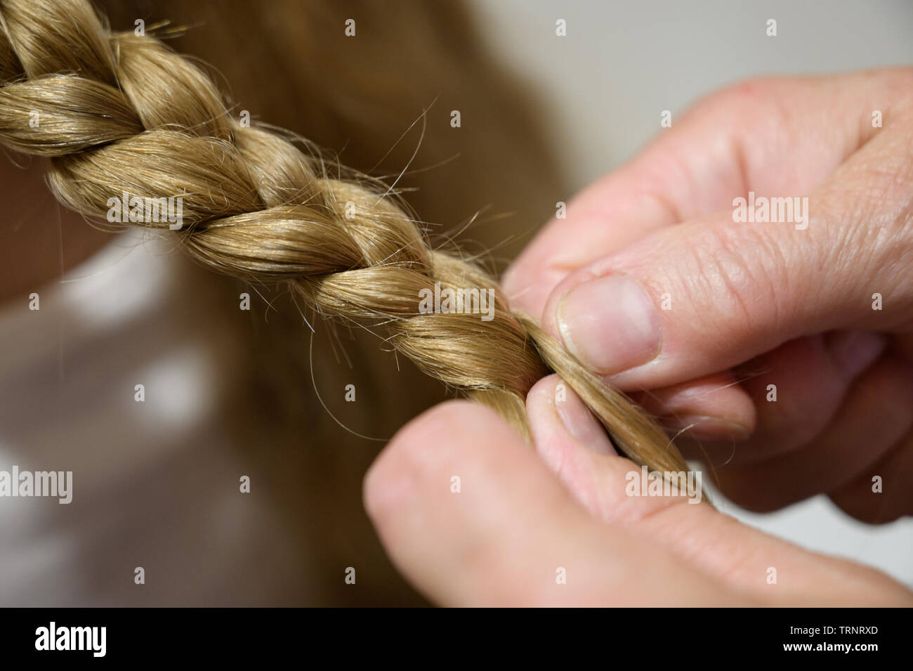randmother make pigtail her granddaughter. Selective focus. Stock Photo