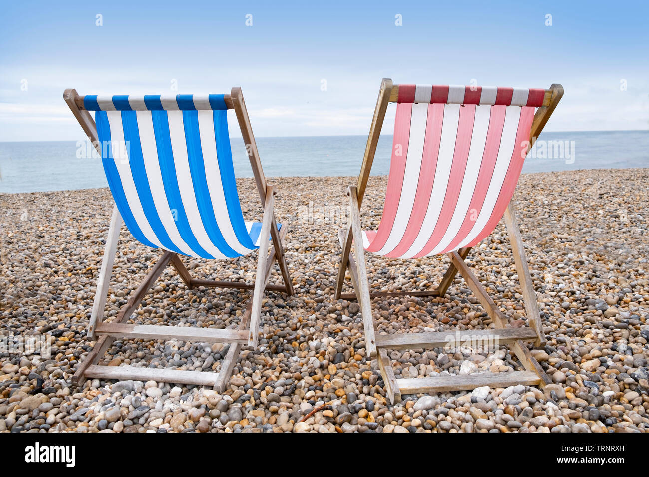 Deckchairs on beach, typical english seaside holiday scene, red and blue stripes representing main political party of labour or conservative Stock Photo