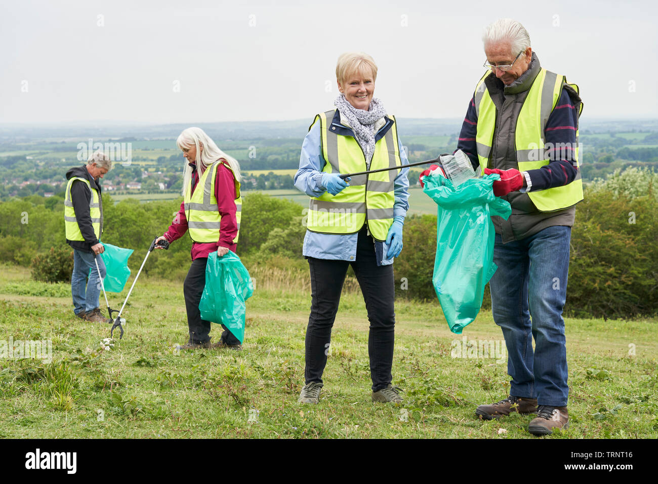 Group Of Helpful Seniors Collecting Litter In Countryside Stock Photo