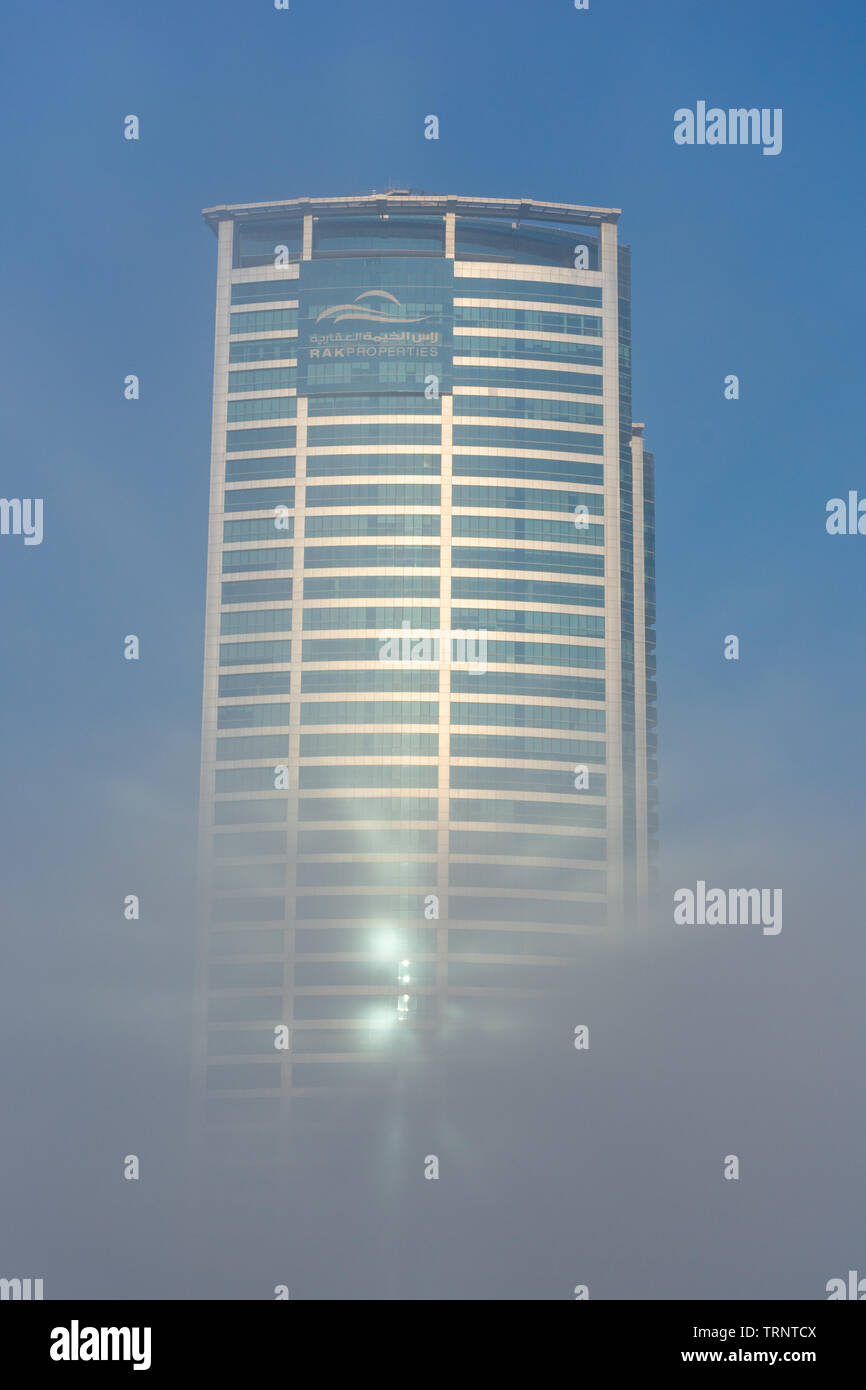 "RAK, RAK/UAE - 10/5/2018 Ras Al Khaimah City in the United Arab Emirates in the early morning fog. Julphur Towers, RAK Properties, in clouds. Stock Photo