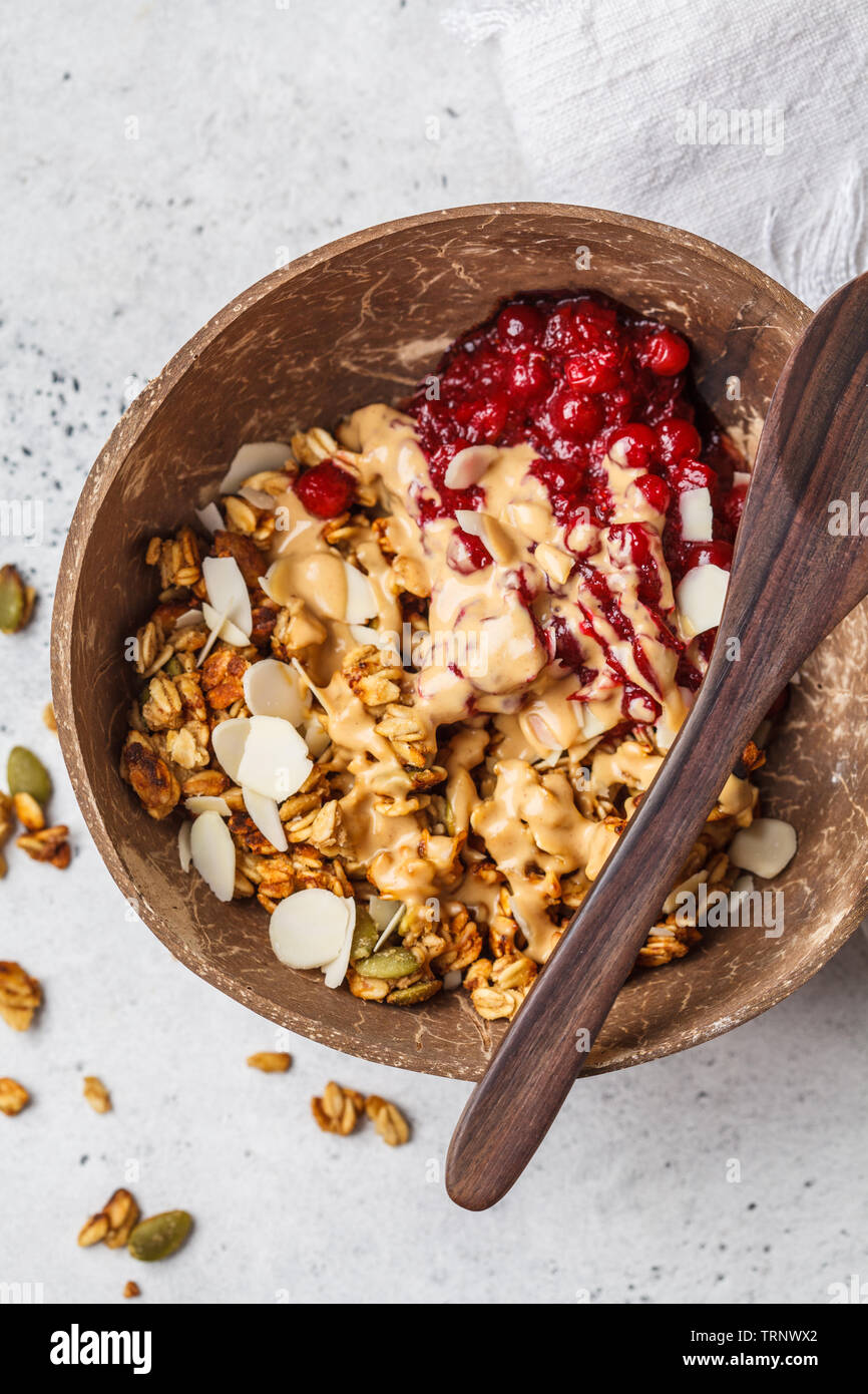 Homemade granola with cranberries and peanut butter in a coconut bowl