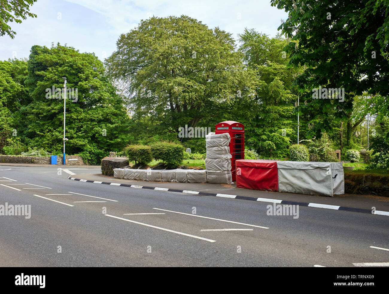A red telephone box on the Isle of Man TT course wrapped up with hay Stock Photo