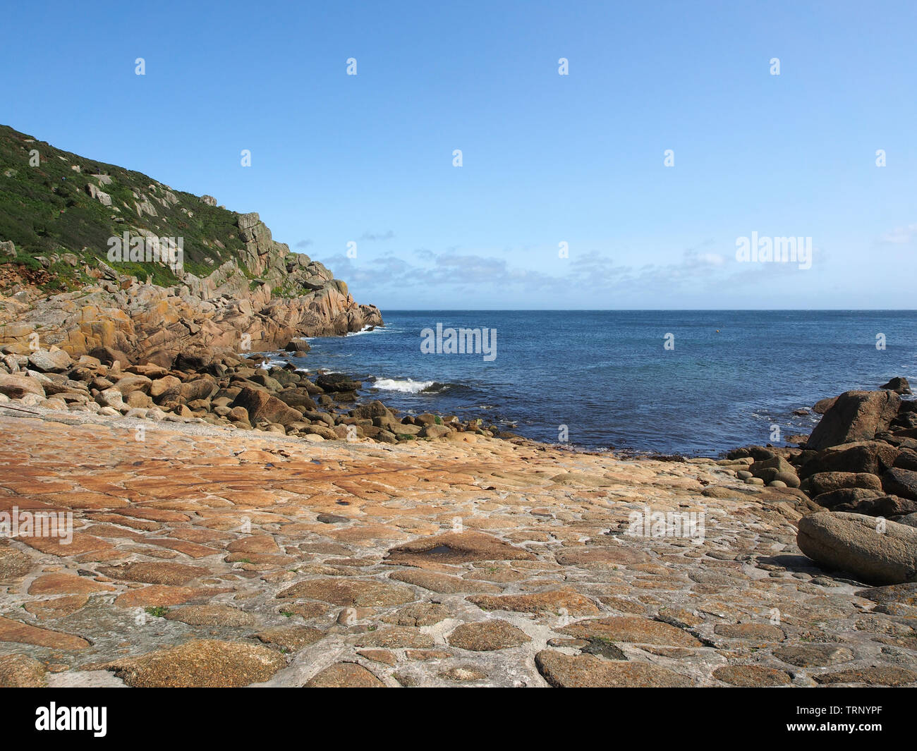 A sunny summers day on the rocky shoreline at Penberth Cove on the Penwith peninsula in Cornwall, England, UK, with blue sea and blue sky. Stock Photo