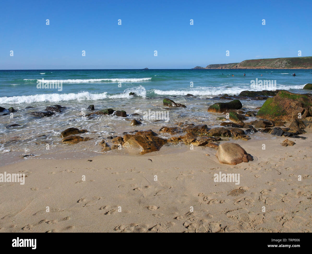 A sunny summers day on the beach in Sennen Cove, Cornwall, England, UK showing the sandy beach and blue sea under a blue sky. Stock Photo