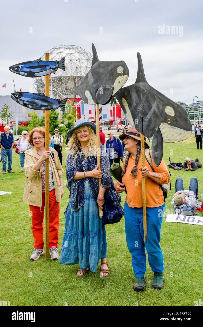 Women with fish and orca placards at No Pipeline Rally, Creekside Park, Vancouver, British Columbia, Canada Stock Photo