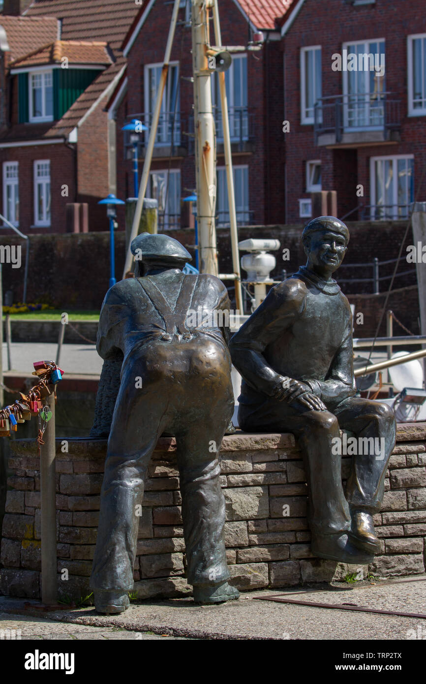 Bronze sculpture of fishermen at edge of harbour. East Frisia. Lower Saxony. Germany. Stock Photo