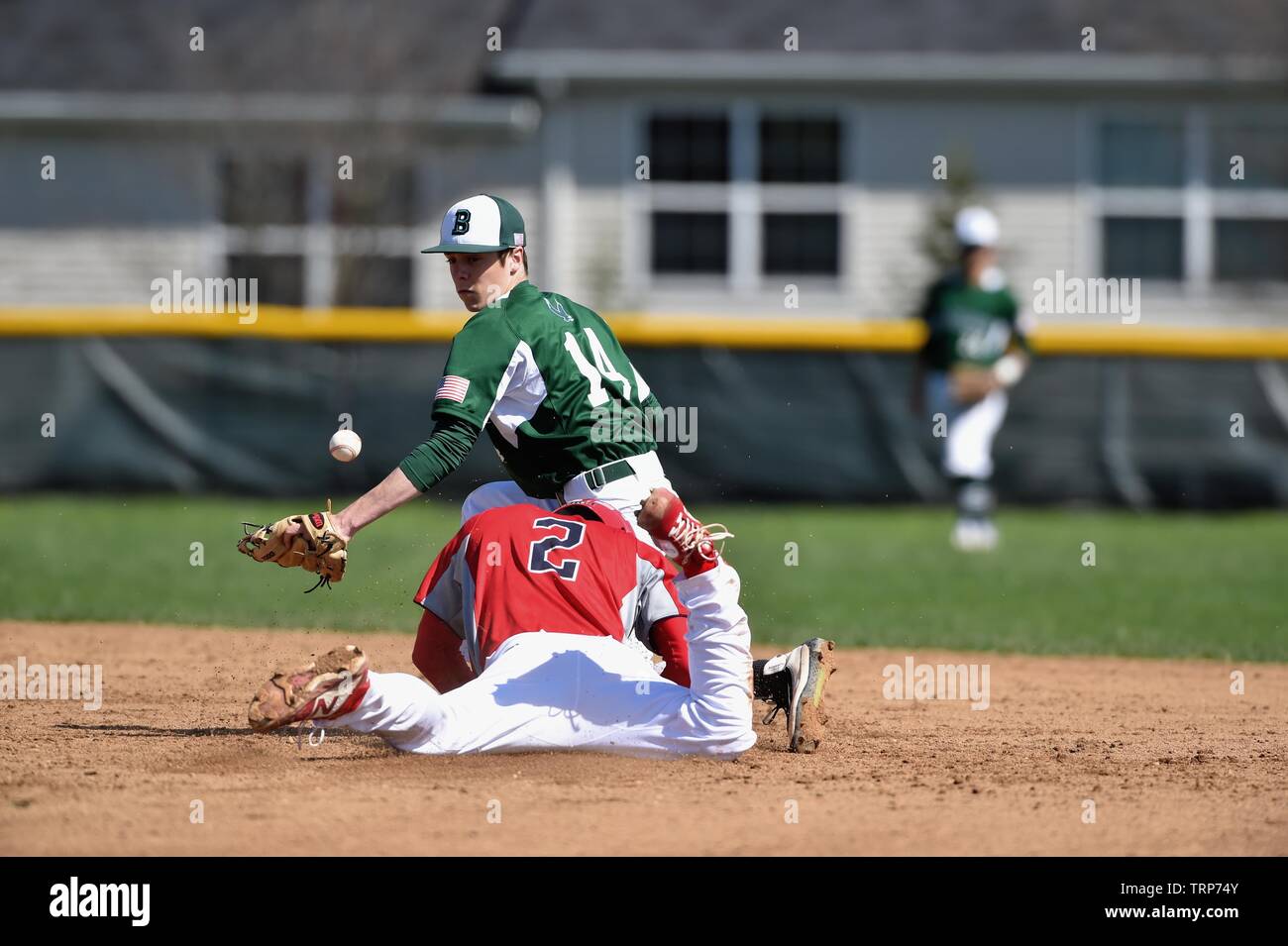 With head-first slide, runner successfully stole second base as the opposing second baseman was unable to secure the throw from the catcher. USA. Stock Photo