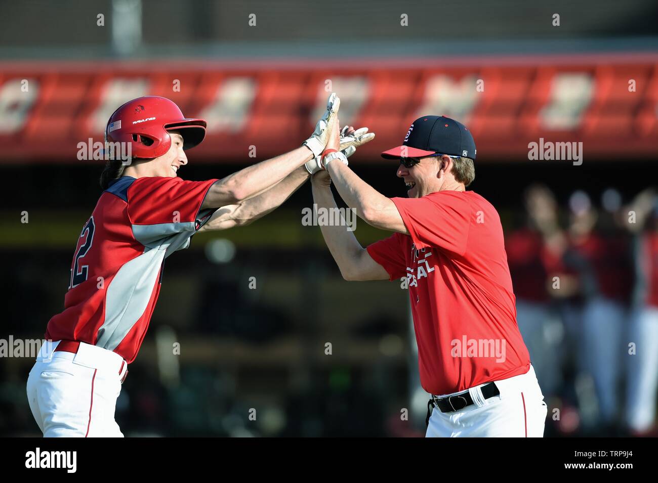 After hitting a home run, a player exchanges high fives with the third base coach on his trip around the bases. USA. Stock Photo