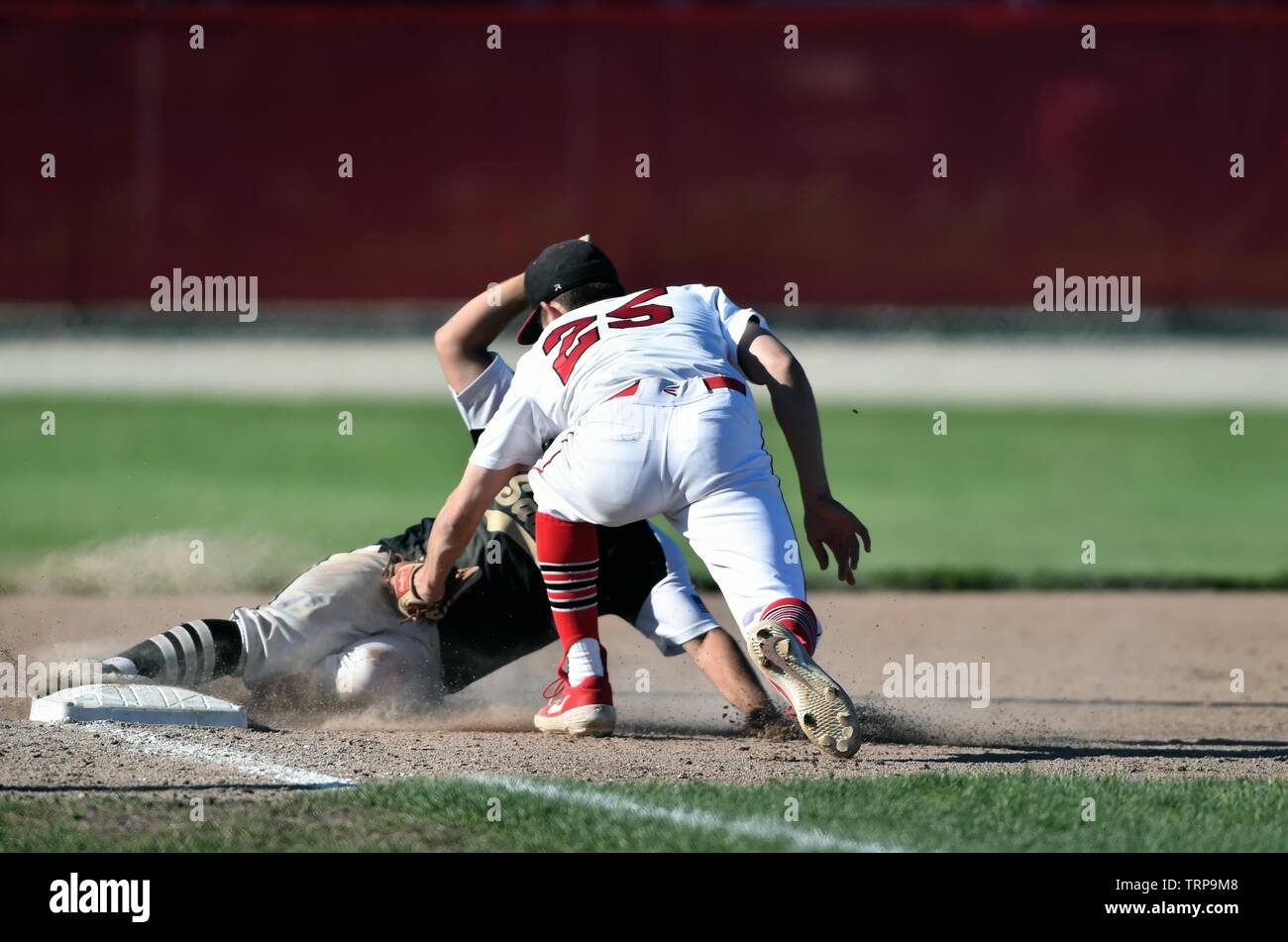 Runner sliding in safely to third base as the opposing third baseman's tag was too late to retire the base runner. USA. Stock Photo