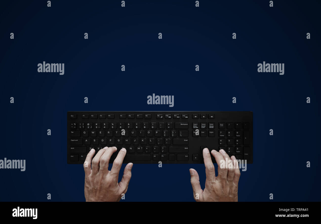 Top view, Hand typing computer keyboard on blue background Stock Photo