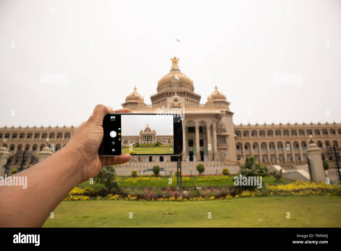 Hands showing of taking a picture of Vidhana soudha with mobile phone Stock Photo