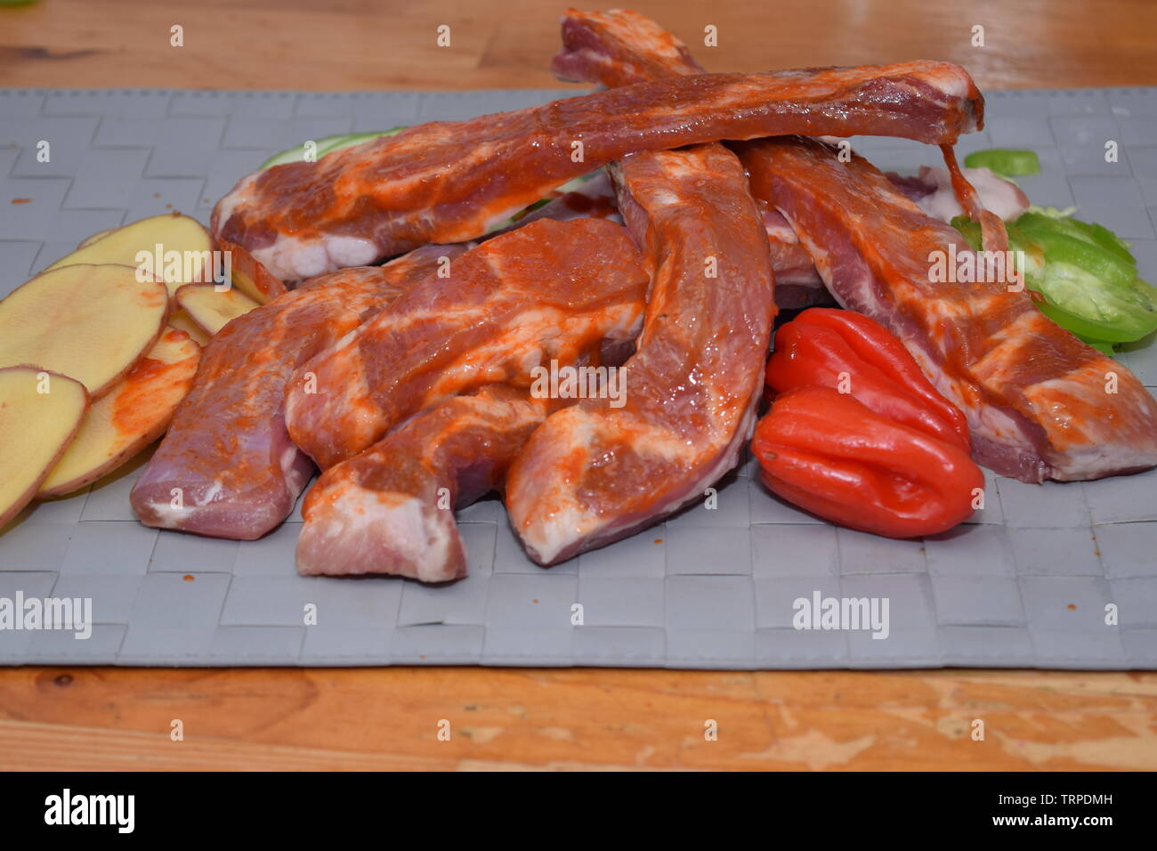 Marinated uncooked pork ribs laid on a clean grey surface with organic sliced vegetables Stock