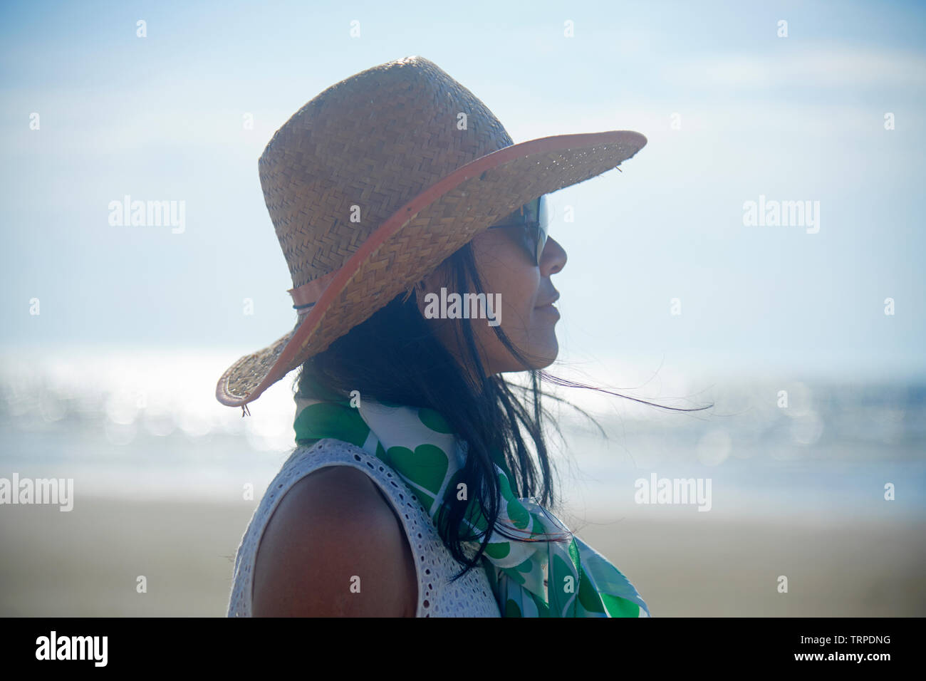 Side profile portrait of a young Asian woman wearing a straw hat and ...